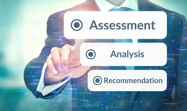 GOAL-ORIENTED RISK ASSESSMENT A person in business attire pointing to the word assessment.